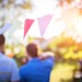 Blød og stemningsfuld sommerfest i haven med guirlander og gæster i baggrunden.
