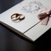 Vielsesringe ligger på en elegant hjemmelavet invitation til guldbryllup.
