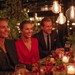 Gæster sidder og lytter til muntre indslag til festen ved middagsbordet.