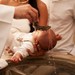 Præst døber en baby under barnedåben i kirken.