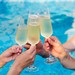 Venner skåler med kolde champagneglas ved poolen og skaber festlig sommerstemning.